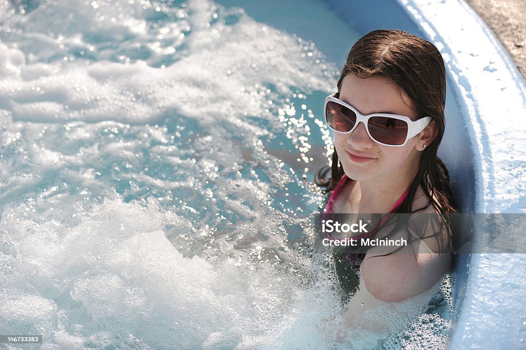 Preteen in a Hot Tub A preteen girl enjoying a soak in an outdoor hot tub on a sunny day. Child Stock Photo