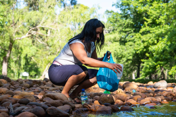 istock Woman collecting plastic recyclables from a pristine river 1467334806