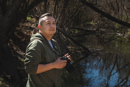 A hispanic man holding a camera looks around at the landscape
