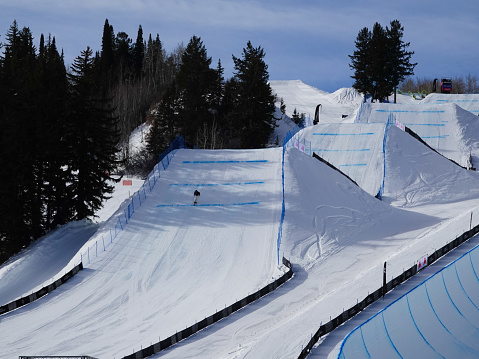 Great view of the snowy mountain slope and the skier jumping air against the background of cloudy sky