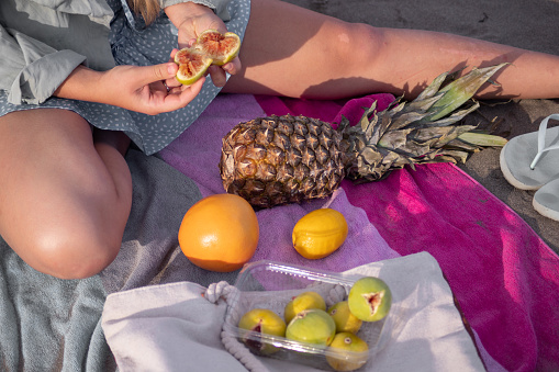 Young woman eating fig, pineapple passion fruit lemon and and grapefruit at the beach