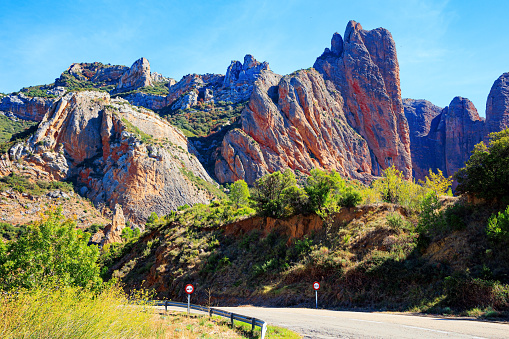 The Mallets of Riglos. Part of the foothills of the Pyrenees. Hot sunny afternoon. Romantic trip to Spain. Aragon. Asphalt highway passes through the rocks.