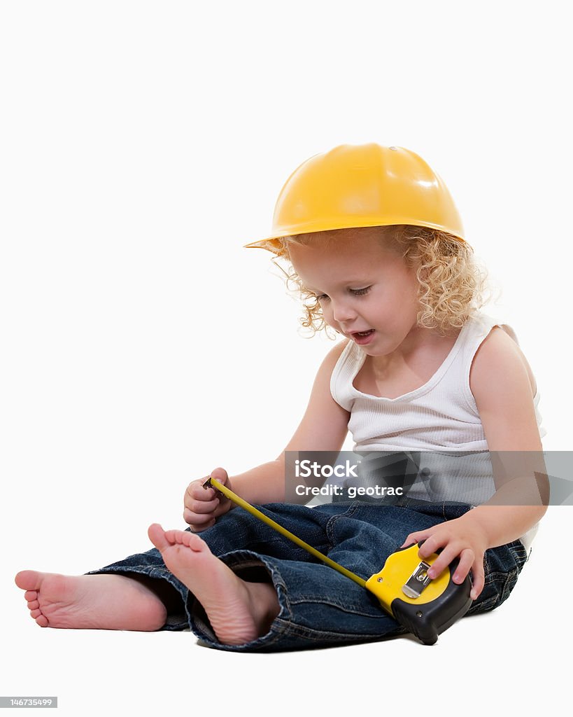 Little construction worker Portrait of an adorable little blond curly hair three year old boy wearing white muscle top and jeans and yellow hard hat dressed like a construction worker holding on to a measuring tape Baby - Human Age Stock Photo