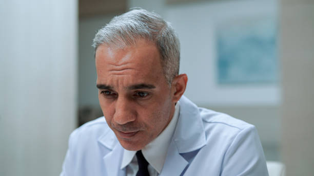 istock Adult Male Doctor Writing Down Notes on Notepad During Video Conference with Client. 1467355328