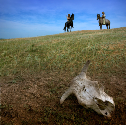 Horsemen archers in steppe landscape in front of cow skull