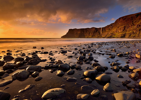 The rock strewn marbled black sandy shoreline of Talisker Bay lit up by the setting sun on a late autumn afternoon.