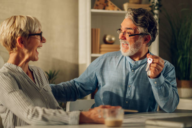 テーブルに座って新しい家の青写真を見ている老夫婦 - senior adult couple computer retirement ストックフォトと画像