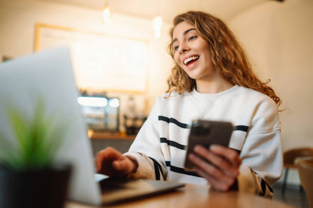 istock Woman sitting in cafe with laptop, typing text message using smart phone while working. 1467364705