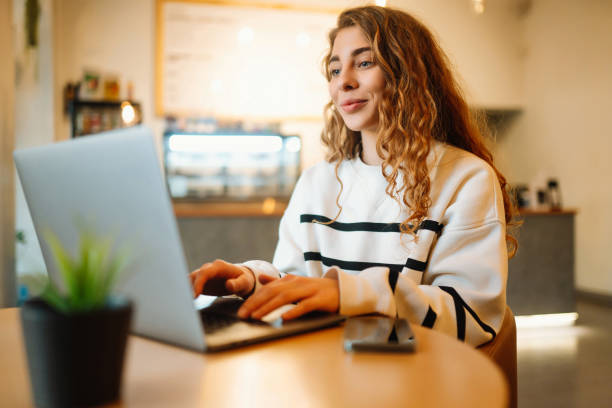 istock Woman sitting in cafe with laptop, typing text message using smart phone while working. 1467364723