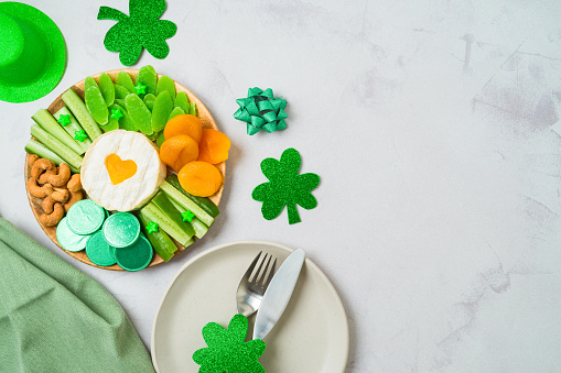 St Patricks day holiday celebration with charcuterie board and  party decorations on bright background. Top view, flat lay