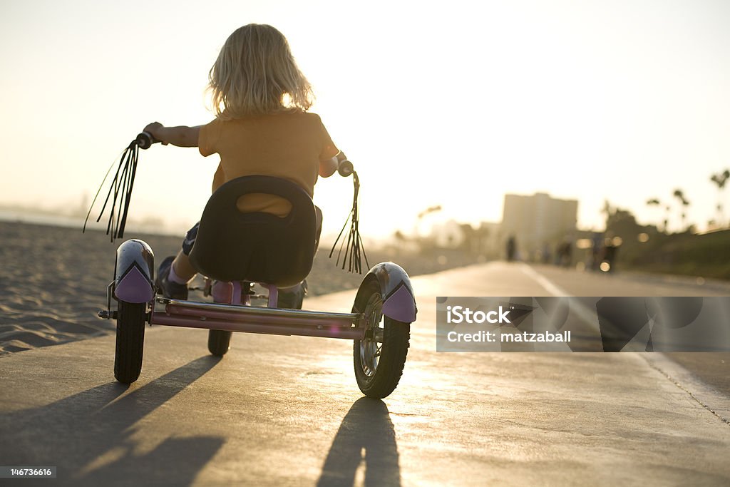 Summer ride A young girl rides her tricycle towards sunset at Long Beach, Ca. Tricycle Stock Photo