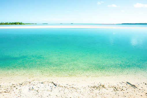 View across intense turquoise coloured agoon to horizon from waters edge.