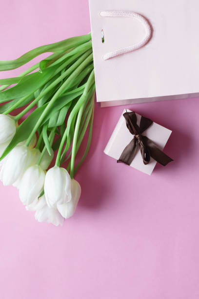 istock White tulips on a pink background and a gift. holiday. 1467371186