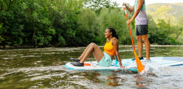 Multiracial couple riding a SUP paddleboard together