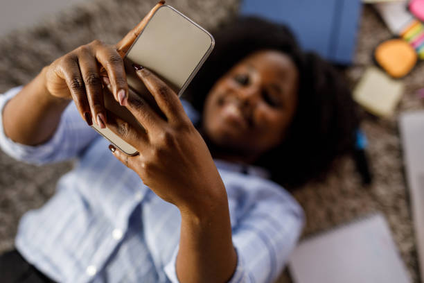 istock Young woman lying on the floor, using smart phone during a break from studying 1467375704