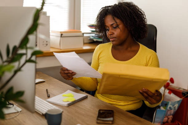 istock Businesswoman unpacking a document from a yellow envelope 1467376586
