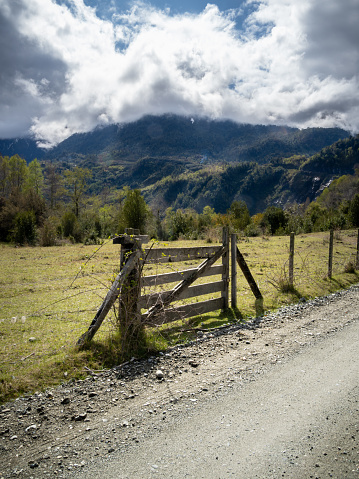 Old wooden gate beside a dirt road on a cloudy day in Los Rios region, southern Chile