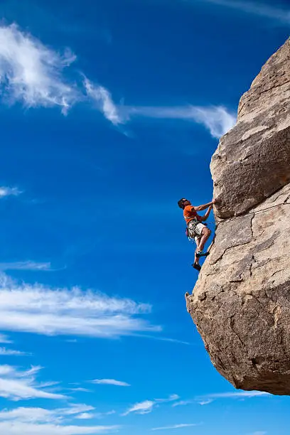 Climber ascends a steep, rock overhang in Joshua Tree National Park, California.