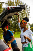 istock Young woman opening car trunk to load groceries with a help of her friend 1467380652
