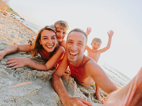 Photo of a smiling family taking a selfie from their beach vacation