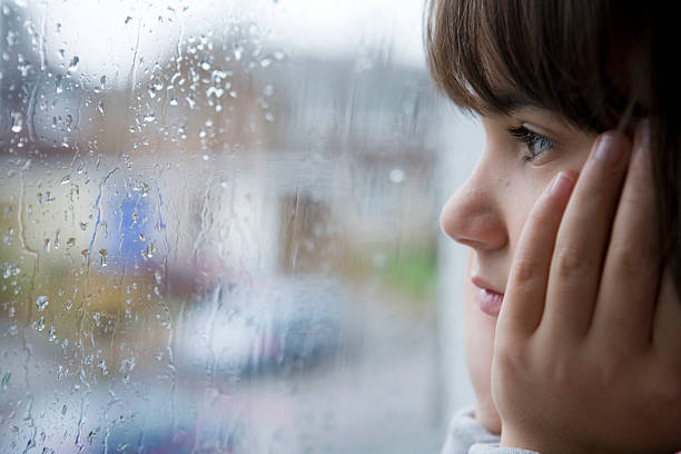 istock Girl looking out a rain splattered window 146739365