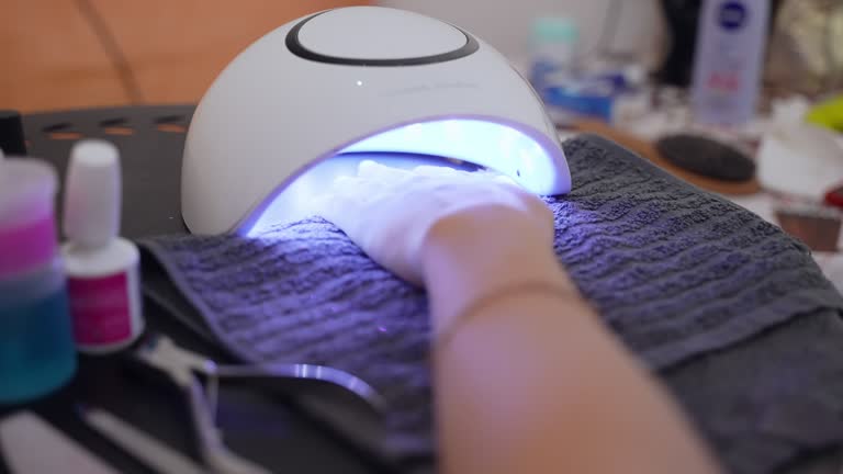 Ultraviolet led lamp used in beauty industry for drying gel nail polish, female hand under the shellac lamp in beauty salon, process of doing trendy gel manicure, art gel nail polish concept