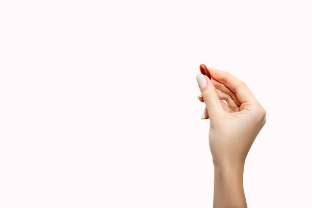 istock Hand holding a pill between thumb and forefinger isolated on white background 1467409064