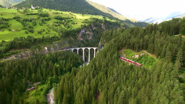 Aerial drone 4k. red swiss train on viaduct bridge in Swiss Alps.