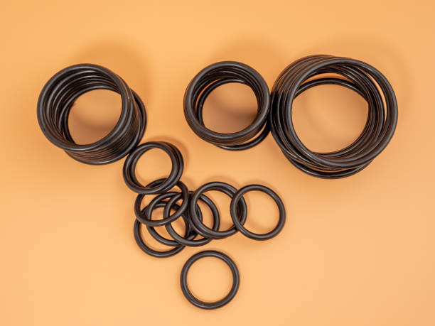 Hydraulic and pneumatic o-rings in black in different sizes on an orange background. Rubber gaskets for plumbing. Hydraulic and pneumatic o-rings in black in different sizes on an orange background. Rubber gaskets for plumbing. copy space. gasket stock pictures, royalty-free photos & images
