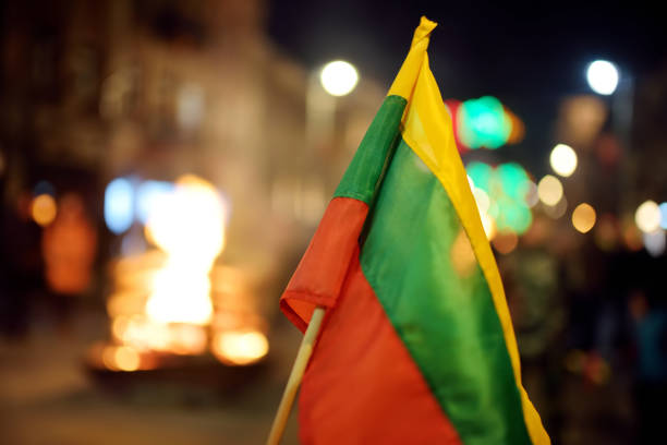 bandeira lituana realizada durante a celebração do dia da restauração do estado em vilnius. fogueiras acesas na avenida gediminas na noite festiva de 16 de fevereiro. - bandeira da lituânia - fotografias e filmes do acervo