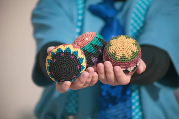 Photo of Girl's hands with three brightly colored knitted circus juggling balls dressed in blue