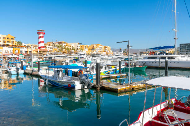 le port de croisière coloré et animé avec des boutiques, des cafés et des bateaux dans la marina le long de la riviera mexicaine à cabo san lucas, au mexique. - marina mexico lighthouse pier photos et images de collection