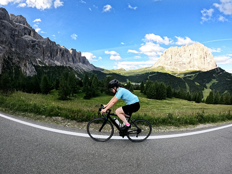 Young woman enjoying cycling vacations in the Dolomites
