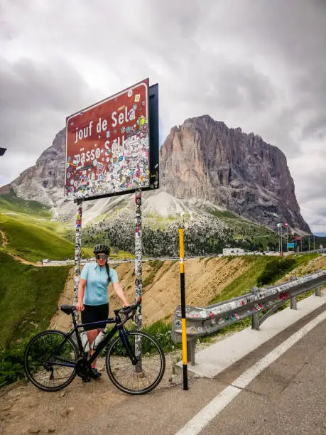 Sporting Young woman posing with her Bicycle next to a mountain pass sign