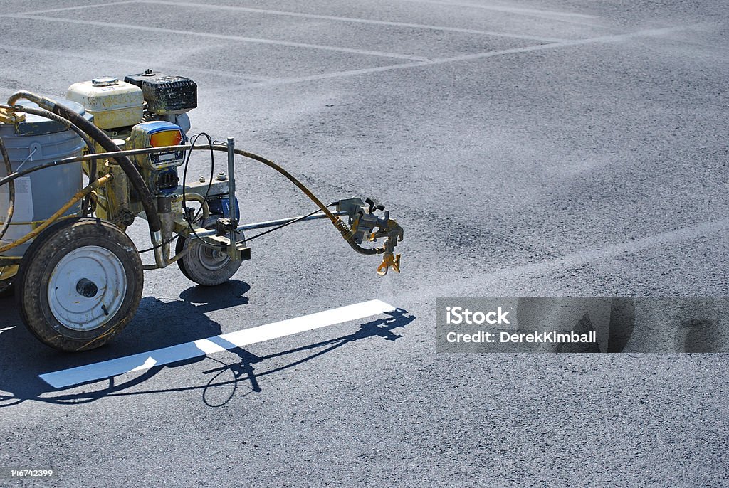 Striping Lines onto fresh asphalt Striping machine painting lines onto fresh asphalt. Parking Lot Stock Photo