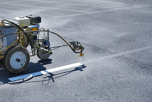 Striping Lines onto fresh asphalt Striping machine painting lines onto fresh asphalt. parking photos stock pictures, royalty-free photos & images