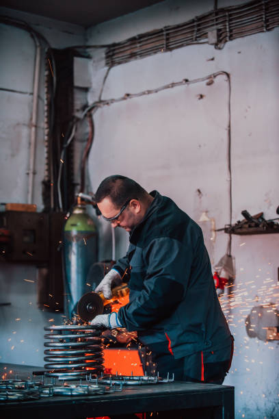 istock Locksmith in special clothes and goggles works in production. Metal processing with angle grinder. Sparks in metalworking. 1467424295