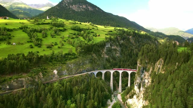 Aerial drone 4k. red swiss train on viaduct bridge in Swiss Alps.