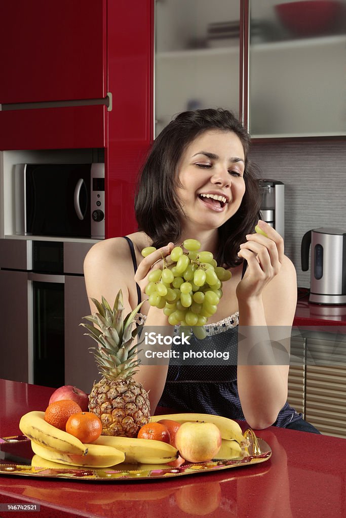 Mujer joven sonriendo y sosteniendo un ramo de uvas - Foto de stock de Adolescente libre de derechos