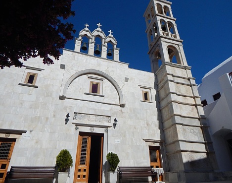 Entrance of A church with a blue dome and a white cross against a blue sky. Kos, Greece