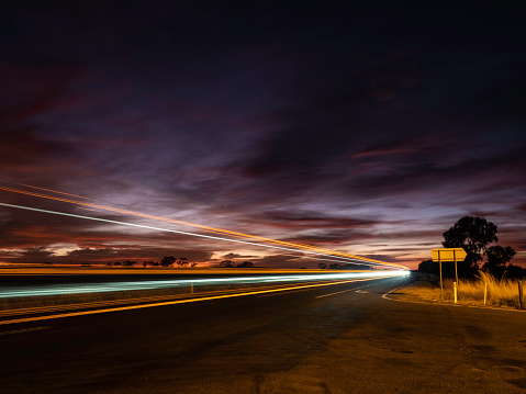 Light trail on remote country road at sunrise