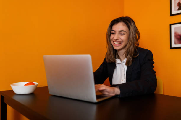 Young smiling woman is working at home office with a laptop