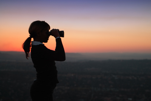 Silhouette of African American Business Woman with Binoculars Standing on a Hilltop