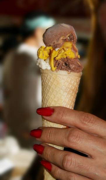 istock Hand with red nails holding an ice cream in a cone 1467430041