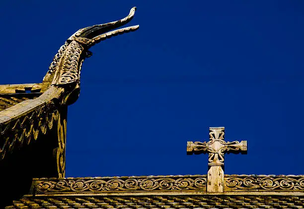 Religious signs on roof of old norwegian stavechurch with blue sky in background. More similar photos in my portfolio.