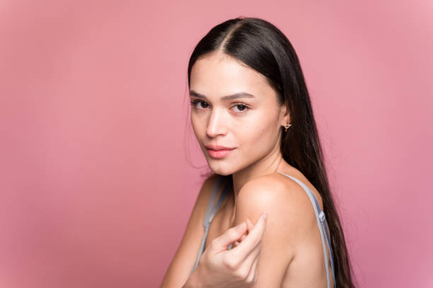 istock Young woman touching her shoulder on pink background in studio 1467433073