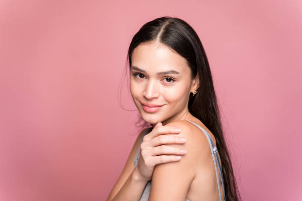 istock Young woman touching her shoulder on pink background in studio 1467433764