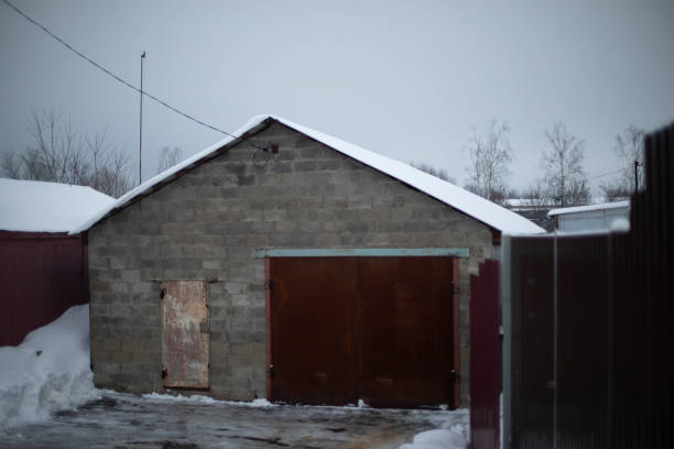 Garage for transport. Concrete house. Rusty gates. Garage block. Ridge roof.