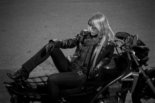 Black and white photo of girl sitting on a motorbike.
