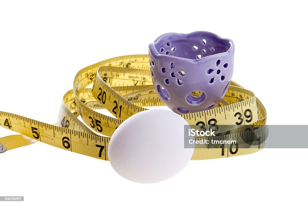 Egg and Tape Measure An egg and purple eggcup with a yellow tape measure.  Conceptual image for dieting, weight loss, etc. Animal Egg Stock Photo